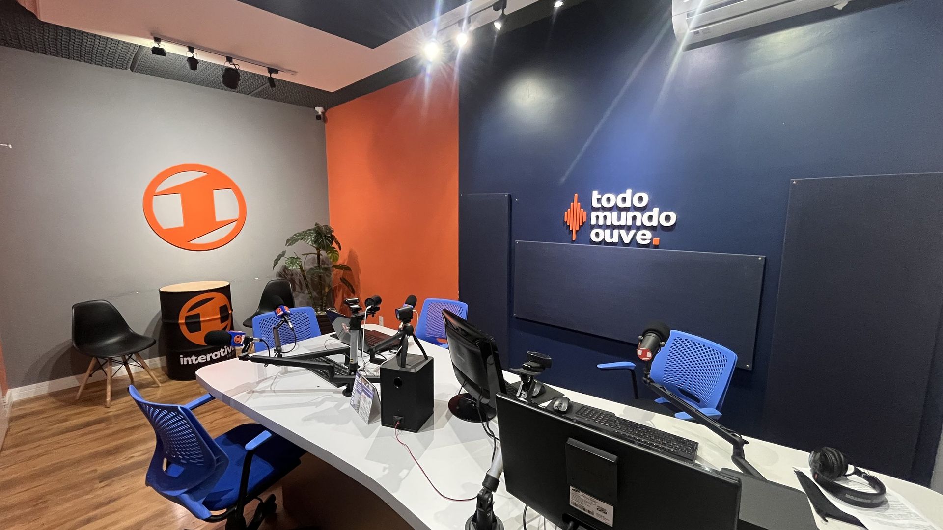 O estúdio da Interativa FM aberto, com a parede laranja e a marca